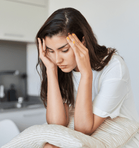 Mujer con síntomas de ansiedad sujetándose la cabeza con tensión